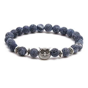 Detail of beaded bracelet set with dark blue stone beads and silver owl charm accent