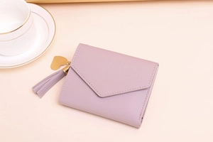 Detail of lavender envelope wallet featuring leather fringe and golden heart charm