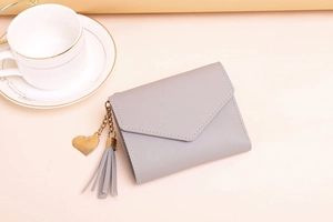 Detailed shot of grey leather tri-fold wallet with tassel and golden heart pendant