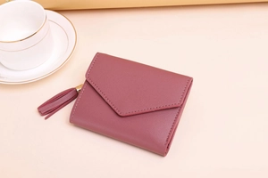 Close-up of textured leather mini wallet with envelope flap and tassel in dusty rose