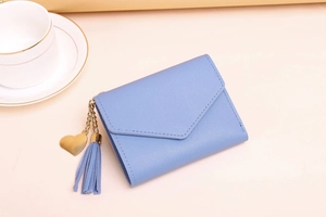 Close-up of light blue trifold wallet with lychee texture and gold heart tassel