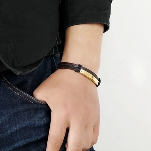 Men's leather bracelet with a polished gold metal plate shown on a model wrist