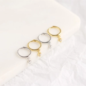 Close-up of gold and silver geometric diamond-set rhobus earrings on white display