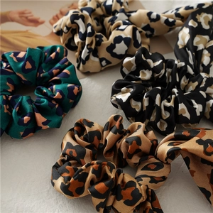 Close-up of leopard print satin scrunchies with rabbit ear bow details and soft silk texture