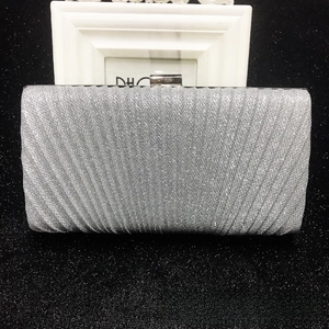 Detail of silver pleated evening clutch with glitter texture and metal clasp