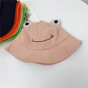 Flat lay of colorful cartoon frog bucket hats with cute 3D eyes in pink and orange