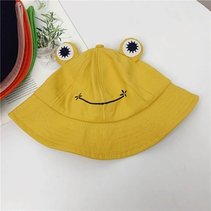 Close-up of yellow frog bucket hat featuring 3D eyes and embroidered smile detail