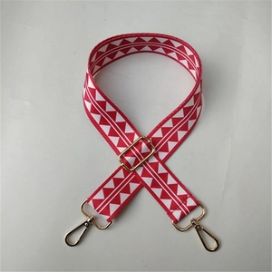 Détail de la bandoulière tissée à motif ethnique rouge et blanc avec boucles dorées