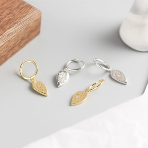 Detailed macro shot of teardrop earrings featuring engraved geometric patterns and small diamonds
