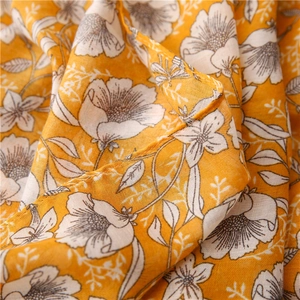 Macro detail of ginger yellow cotton linen fabric with hand-drawn floral print patterns