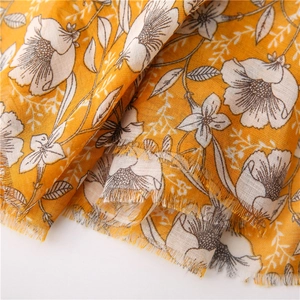 Detail of yellow cotton linen scarf featuring white gardenia print and frayed edges