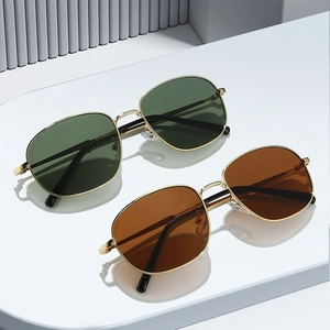 Modern oval metal sunglasses in green and brown lenses on a minimalist pedestal