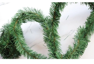 Macro view of realistic dark green PVC artificial pine needle garland on marble background