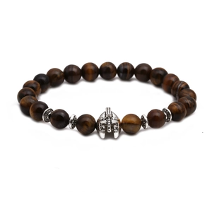 Detailed macro of a brown tiger eye beaded bracelet featuring a silver Spartan helmet charm