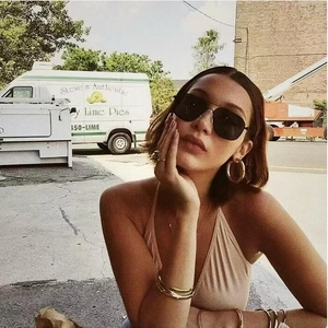 Close-up of golden oversized hoop earrings and black aviator sunglasses in street style