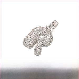 Macro detail of iced-out letter R pendant with rhodium plating and cubic zirconia
