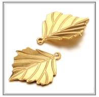 Macro shot of two golden leaf-shaped pendants showing metallic texture and vein details