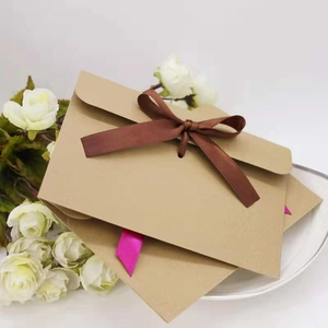 Close-up of vintage kraft paper envelopes with brown and rose red silk ribbon bows