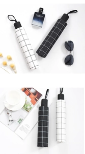 Flat lay of plaid umbrellas with black and white grid patterns and elegant accessories