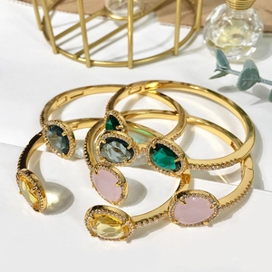 Detail of gold-plated bracelets featuring colorful gemstones and micro-pave zircons