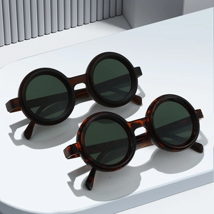 Retro-Sonnenbrille mit rundem Rahmen in Dunkelbraun und Schildpatt auf weißem Podest