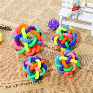 Close-up of four colorful woven pet bell balls in various sizes on a newspaper background