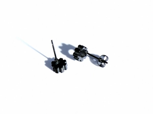 Detailed view of industrial gear stud earrings in matte black finish on white background
