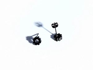 Detailed macro shot of industrial matte black gear-shaped titanium steel stud earrings