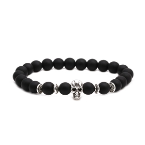 Macro shot of matte black beaded bracelet featuring a detailed silver skull accent