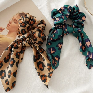 Detail view of leopard print satin hair scrunchies in brown and green with stylish long bows