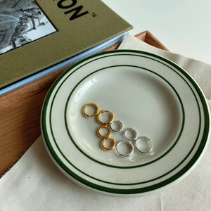Minimalist silver and gold hoop earrings in various sizes arranged on a white ceramic plate