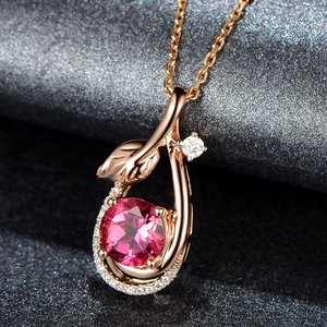 Macro shot of rose gold leaf pendant with pink gemstone and small white accent stone
