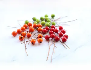 Close-up of artificial berries in red, orange, and green for DIY floral crafts