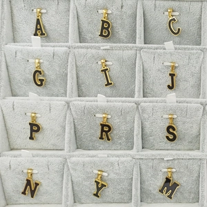 Varios colgantes de letras iniciales en oro y negro en una bandeja de joyería