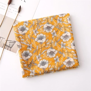 Detail showing ginger yellow floral scarf with cotton linen texture and white flower print