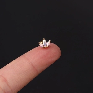 Golden crown cartilage stud earring with marquise stones held on fingertips for scale