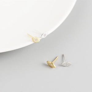 Detailed close-up of gold and silver minimalist eye-shaped stud earrings with star engraving