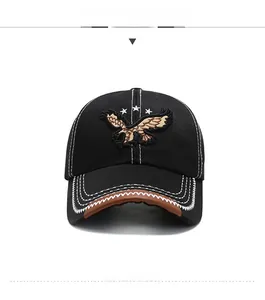 Detail of black baseball cap with eagle embroidery and brown leather brim stitching