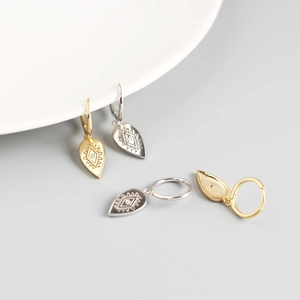 Detail of drop-shaped S925 silver hoop earrings with sun engraving and white zircon inlay