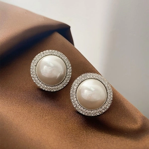 Luxury pearl stud earrings with sparkling crystals and silver needle on brown silk