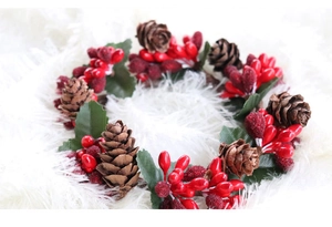 Detail van kerstkrans met rode bessen, dennenappels en groene bladeren op pluche