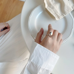 Close-up of a minimalist irregular 925 silver wave ring worn on index finger