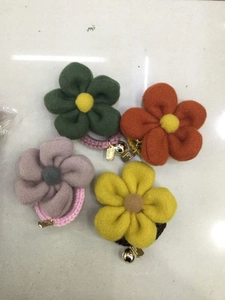 Detail of wool flower hair ties in four colors with small metal bells and tags