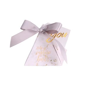 Detail view of pyramid wedding favor box with marble texture and golden lettering