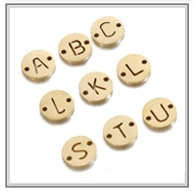 Detail of round golden stainless steel tags with engraved letters and double holes for DIY