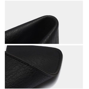 Détail macro de la texture du cuir noir et des coutures précises de la pochette à lunettes