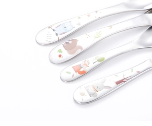 Close-up of stainless steel cutlery handles with colorful cartoon owl and fox patterns