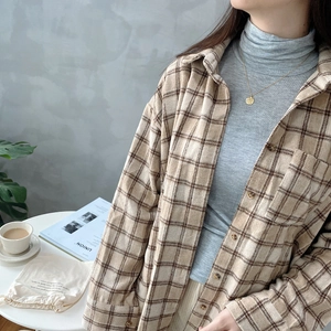 Detail view of brown plaid shirt styled with a grey turtleneck and casual accessories