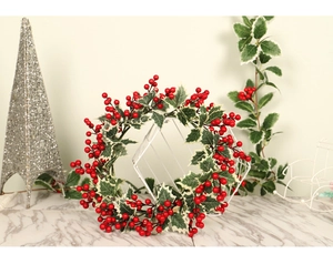 Détail d'une couronne de Noël avec des baies rouges et des feuilles bordées de blanc