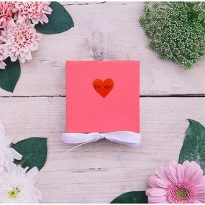 Pink gift box with red heart for you print and white ribbon on wooden background